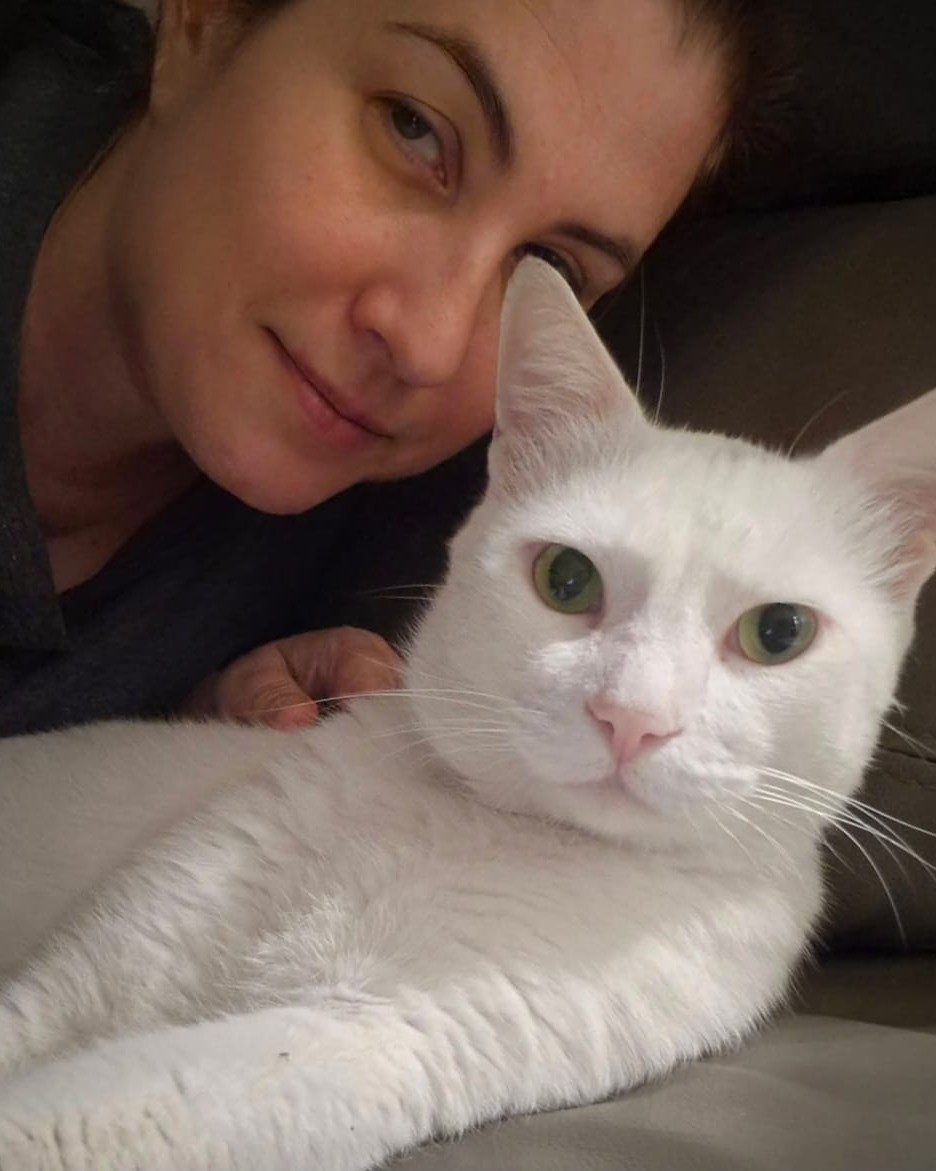 Erika cuddling a white cat during an in-home visit in Dubai